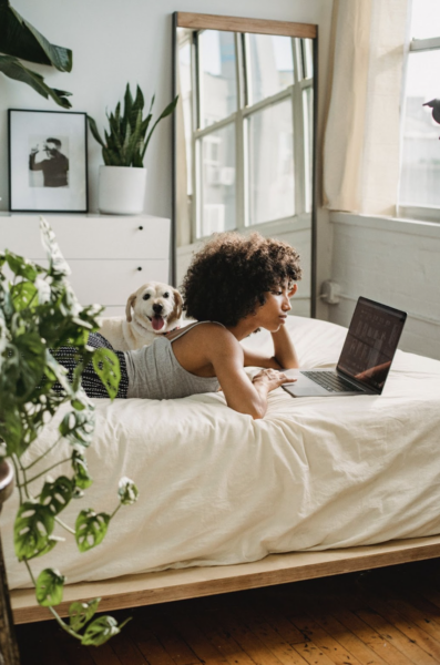 Black woman on bed looking at computer
