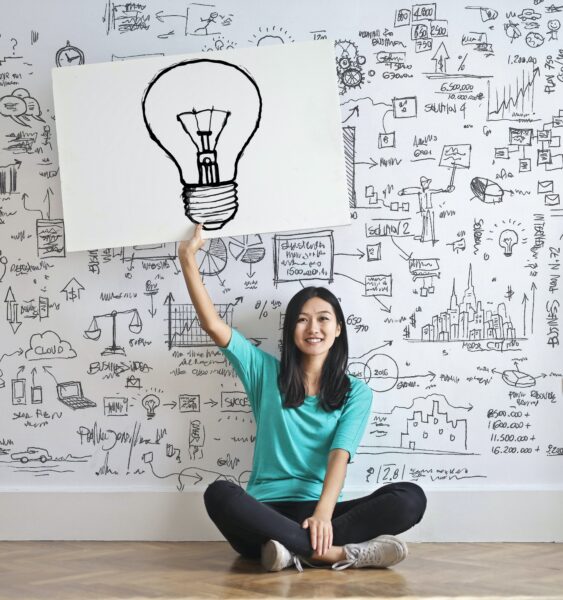 Woman sitting down holding a drawing of a lightbulb