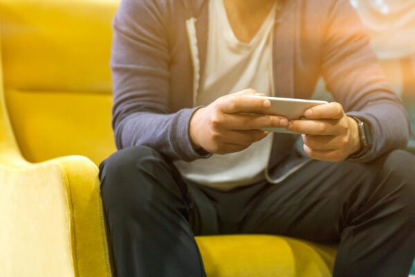 Young man sitting on couch typing on smartphone